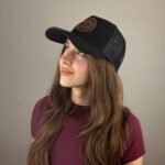 Black trucker cap with suede finish, leather Troy Life logo patch, and breathable mesh back